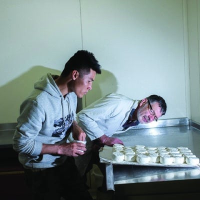 Ahmed Rezai, exilé afghan installé à Caen, et Éric Robert, propriétaire de la Chèvrerie du Mesnil, à Carentan-les-Marais, en pleine opération de salage des fromages fermiers.