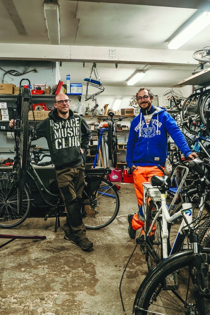 Clément (à droite) et Stefan (à gauche) réparent ou électrifient les vélos des habitants de la Suisse normande.