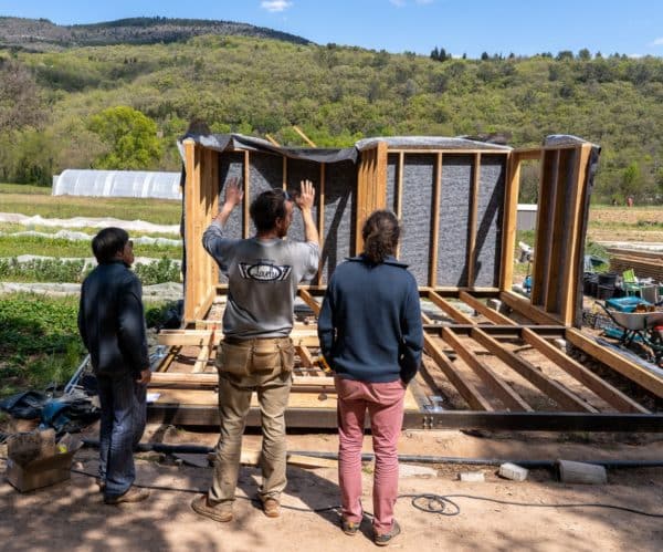 © Bastien Defives. Pose ossatures murs (extérieurs et intérieurs) et ossatures toiture. Projet BatiAlim. Formation à l'autoconstruction agricole donnée par 3PCo. Sur la parcelle du Jardin de Campeyrou. Avec l'aide du collectif Résilience alimentaire de Lodève. Campeyrou, Lodève. Hérault.